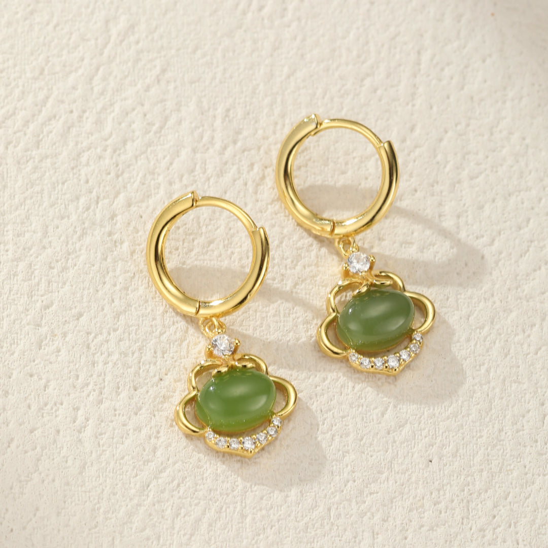 Boucles d’oreilles plaquées or avec une pierre de jade verte ovale et des zircons cubiques, ornées d'un motif floral stylisé.