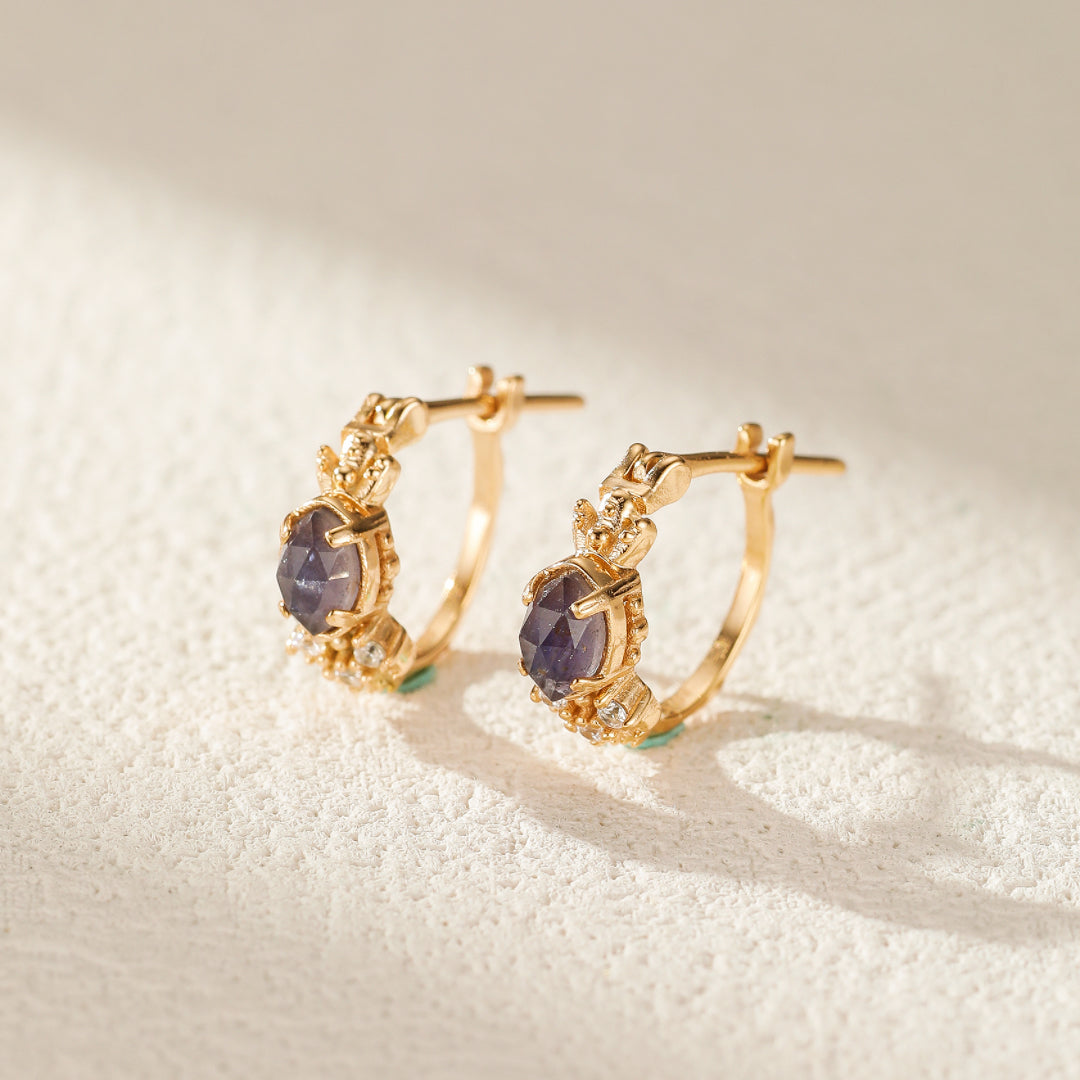 Paire de boucles d'oreilles créoles plaquées or avec une pierre centrale ovale violette et de petites pierres blanches incrustées, design élégant.