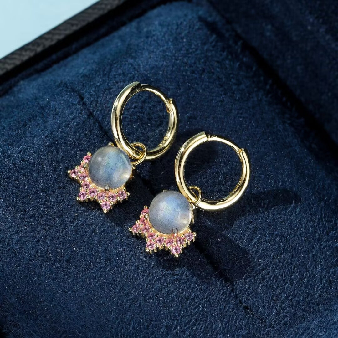 Boucles d'oreilles créoles plaqué or ornées d'une pierre de labradorite grise et de petites pierres roses disposées en étoile.