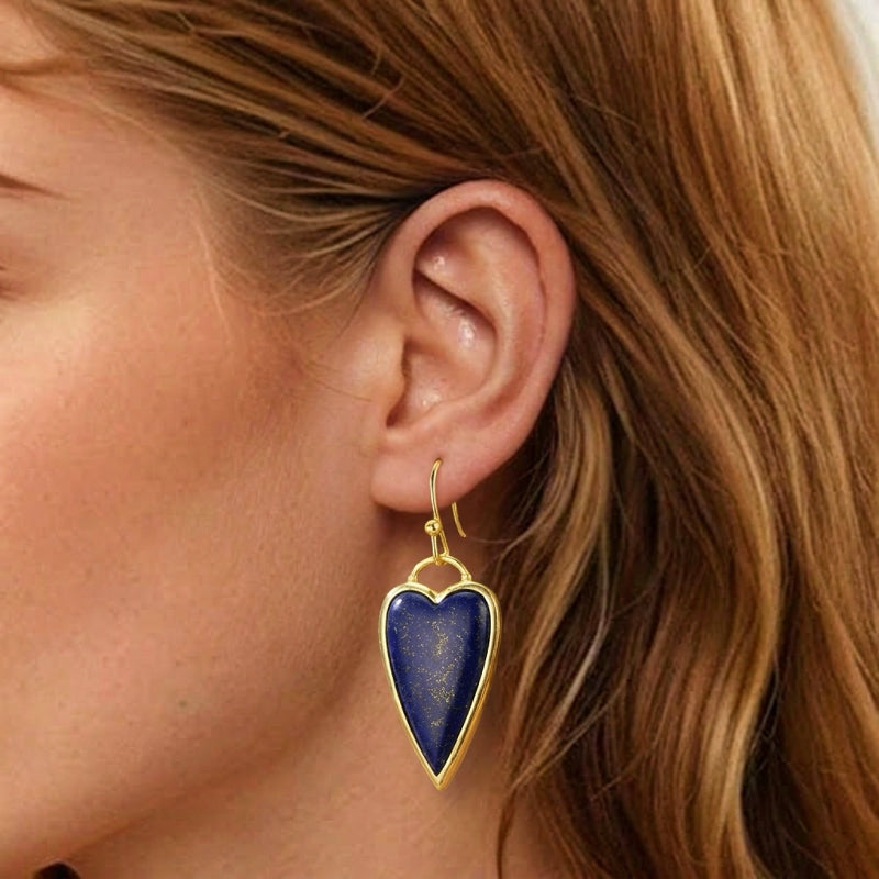 Boucles d'oreilles cœur en lapis-lazuli avec une monture dorée, portées par une femme