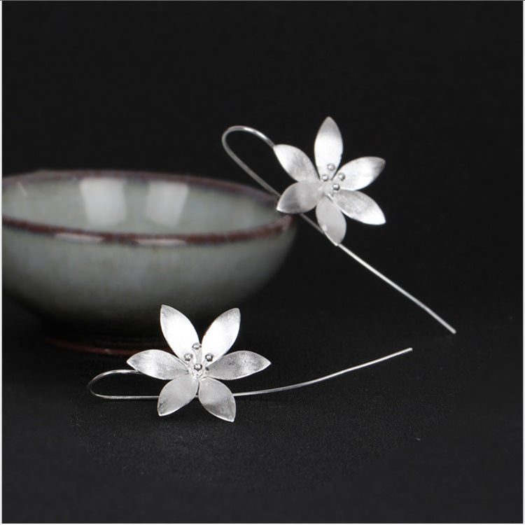 Boucles d'oreilles pendantes en argent avec motif de fleur de lotus éclose et de petites perles au centre.