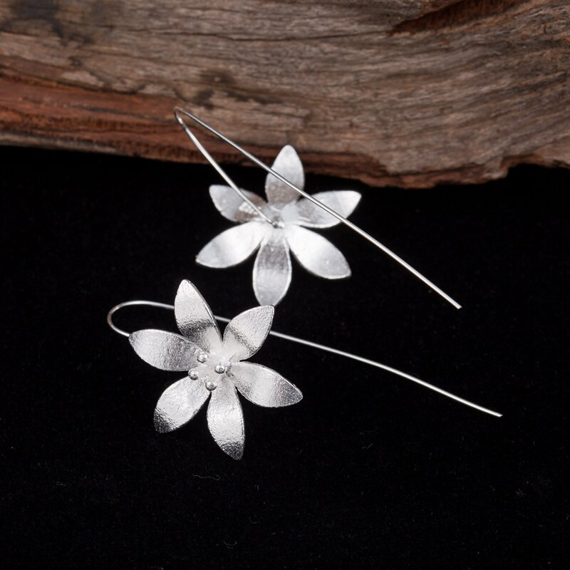 Boucles d'oreilles pendantes en argent sterling représentant des fleurs de lotus écloses avec des détails subtils au centre.