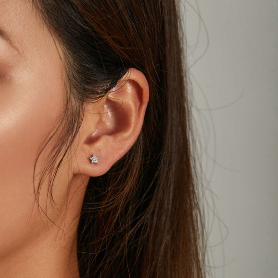 Boucles d'oreilles étoiles en argent 925, serties de petites pierres scintillantes, portées à l'oreille.