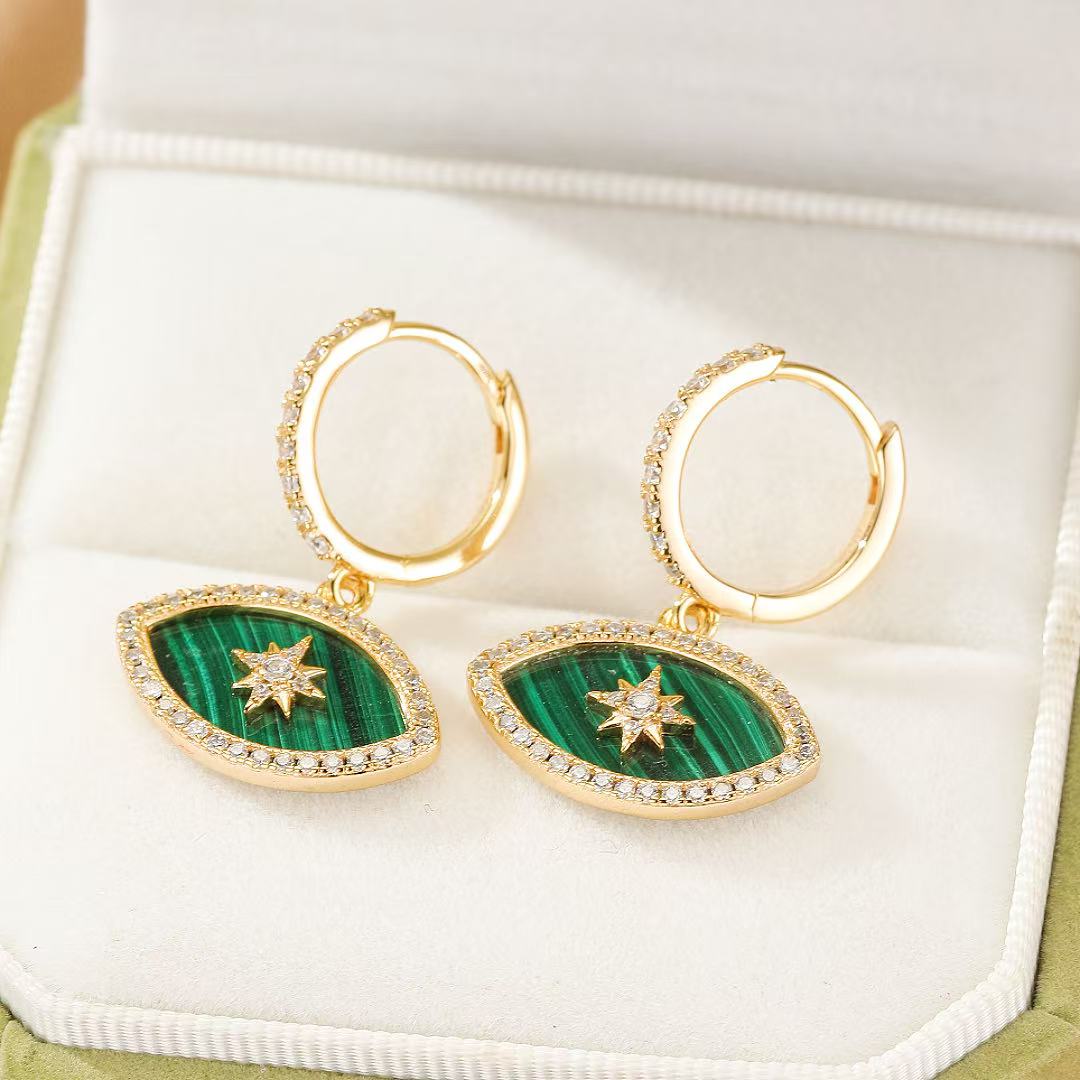 Boucles d'oreilles créoles plaqué or serties de zircons, ornées de pendentifs œil en malachite avec étoile centrale scintillante.