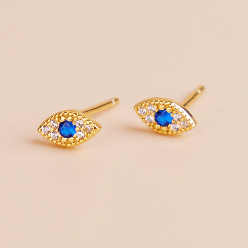 Paire de clous d'oreilles plaqué or en forme d'œil bleu serti de zirconiums blancs brillants, symbolisant le mauvais œil.
