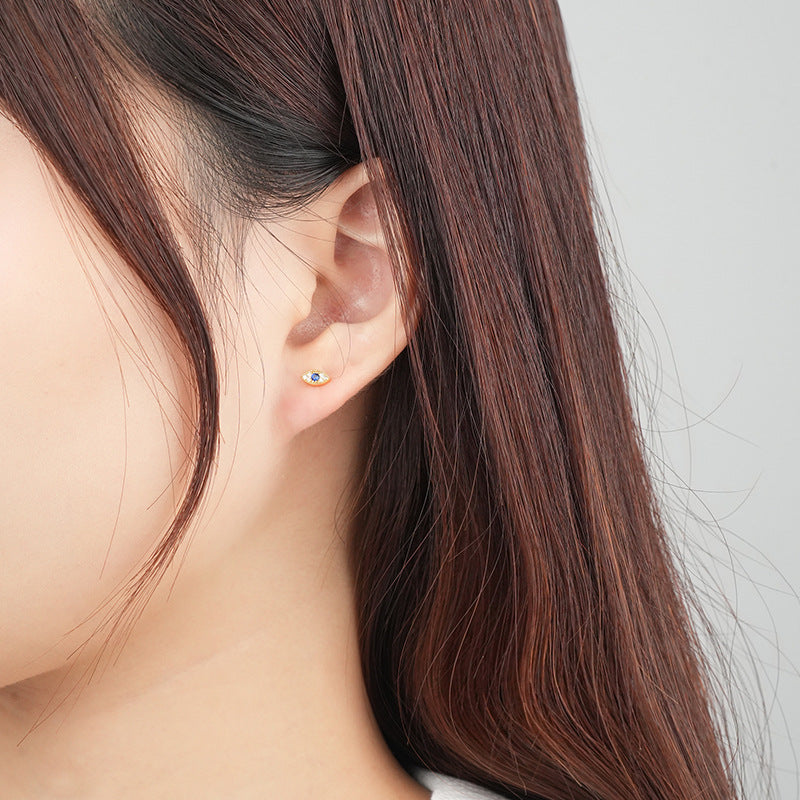 Boucle d'oreille œil bleu plaqué or portée par une femme