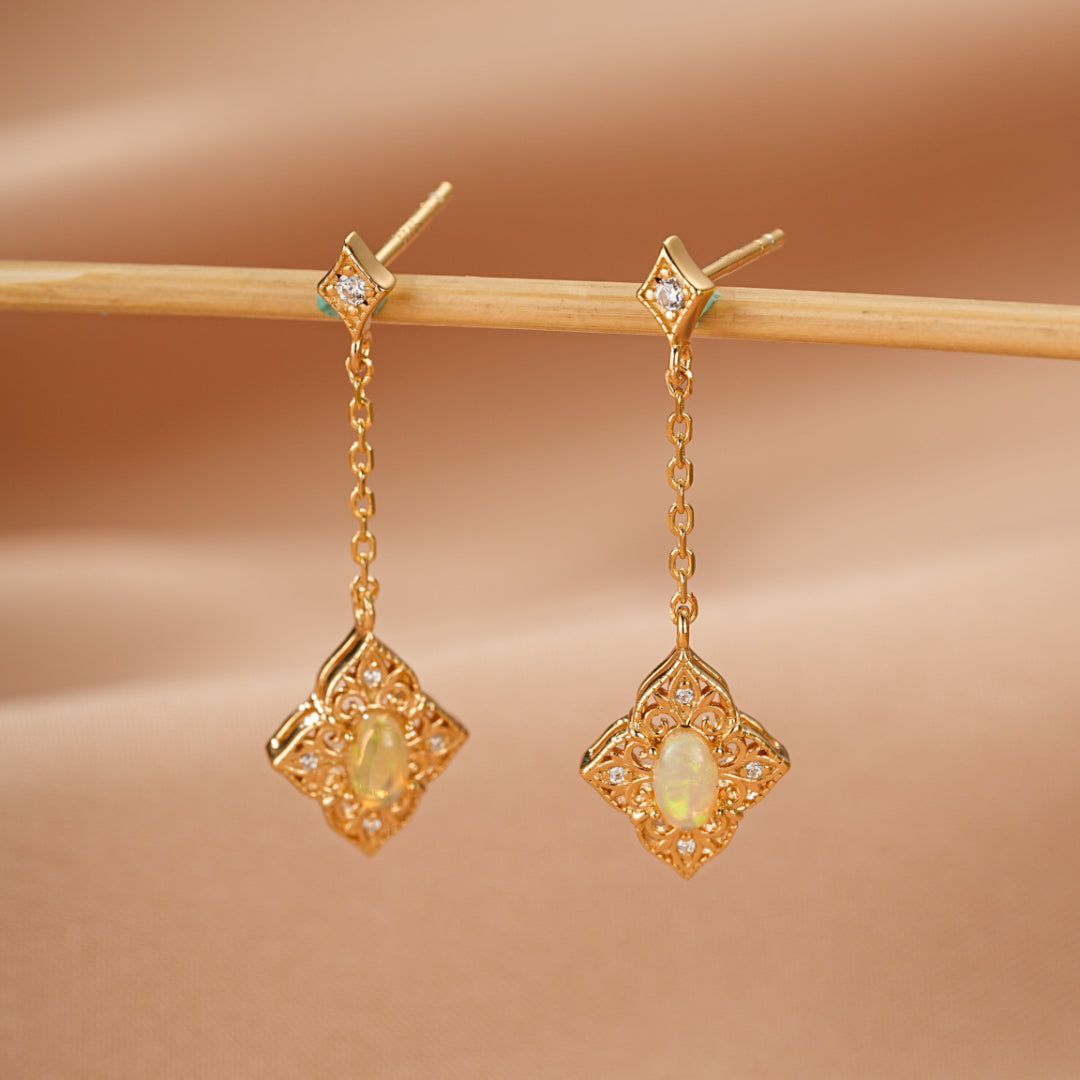 Boucles d'oreilles pendantes en argent plaqué or 10K ornées d'opales ovales et de petites pierres scintillantes, suspendues à une chaîne délicate.