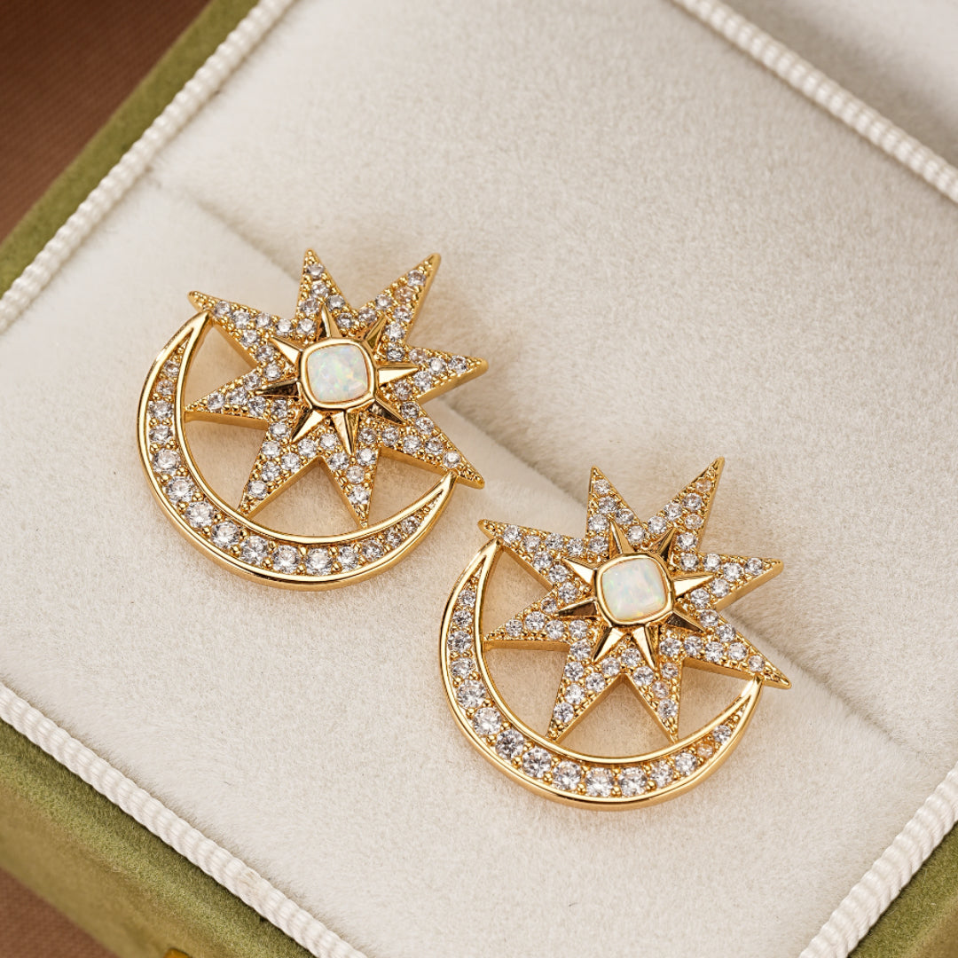Boucles d'oreilles en forme de croissant de lune et d'étoile, serties de petites pierres scintillantes et d'une opale carrée au centre, en métal doré.