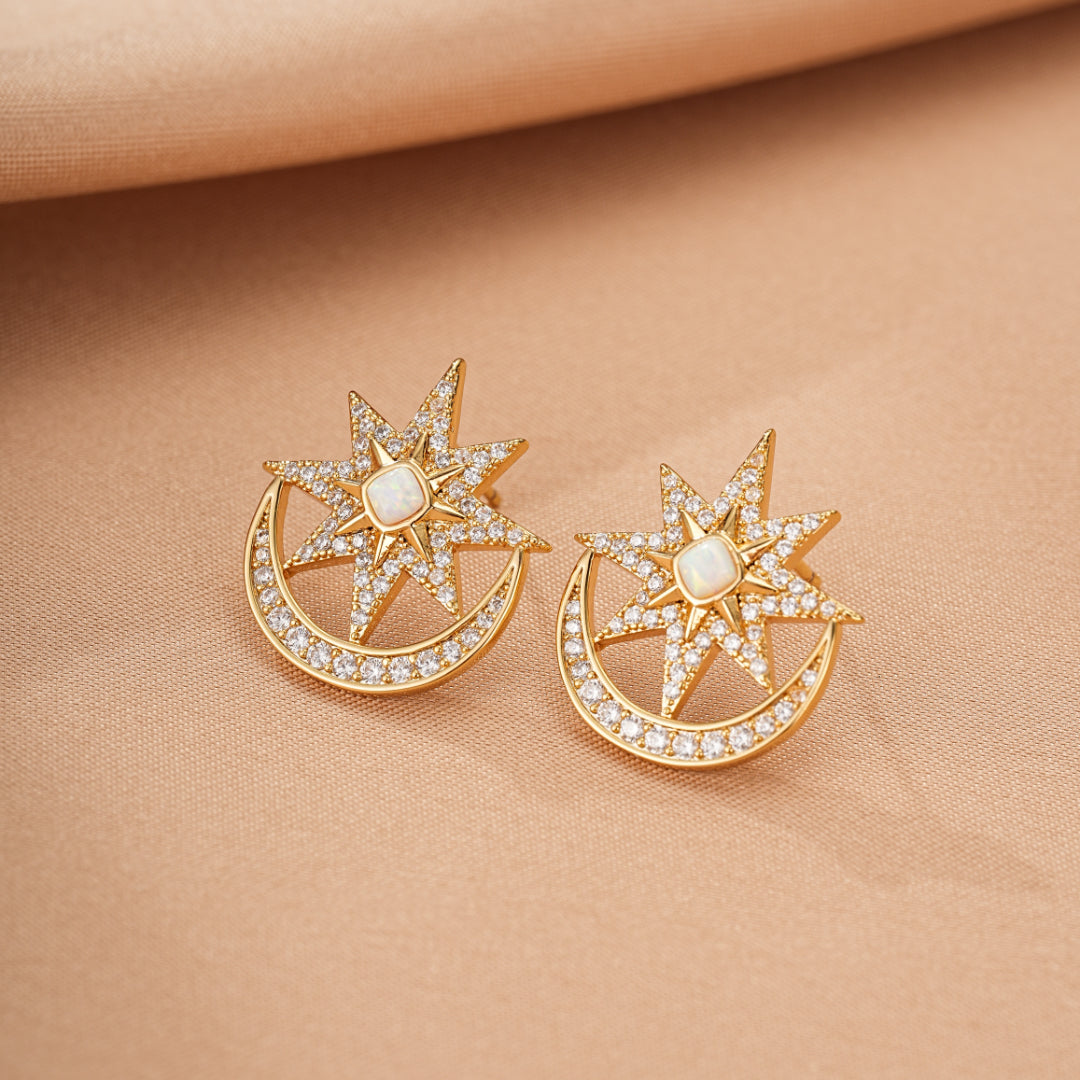 Paire de boucles d'oreilles en forme de lune et d'étoile ornées d'opale et de diamants scintillants, en or jaune, sur fond beige.