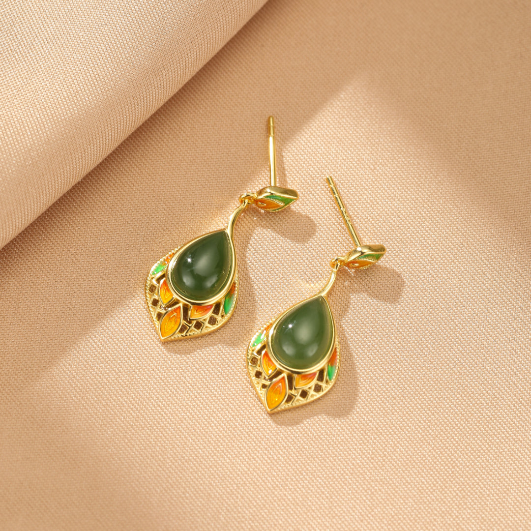 Boucles d'oreilles pendantes en argent plaqué or avec une pierre de jade verte en forme de goutte et des détails émaillés colorés rappelant des feuilles.