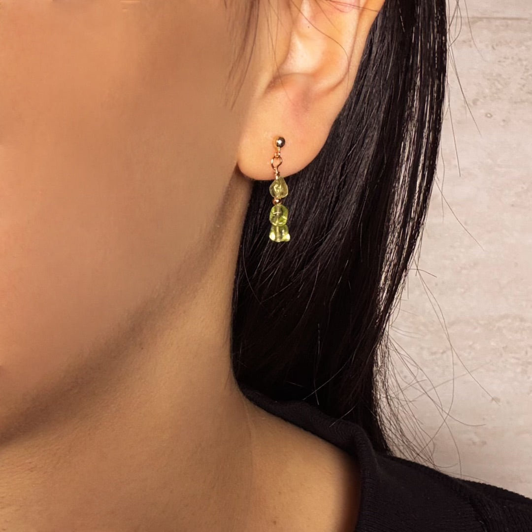 Boucles d’oreilles pendantes en argent plaqué or avec trois perles de péridot en forme de goutte.