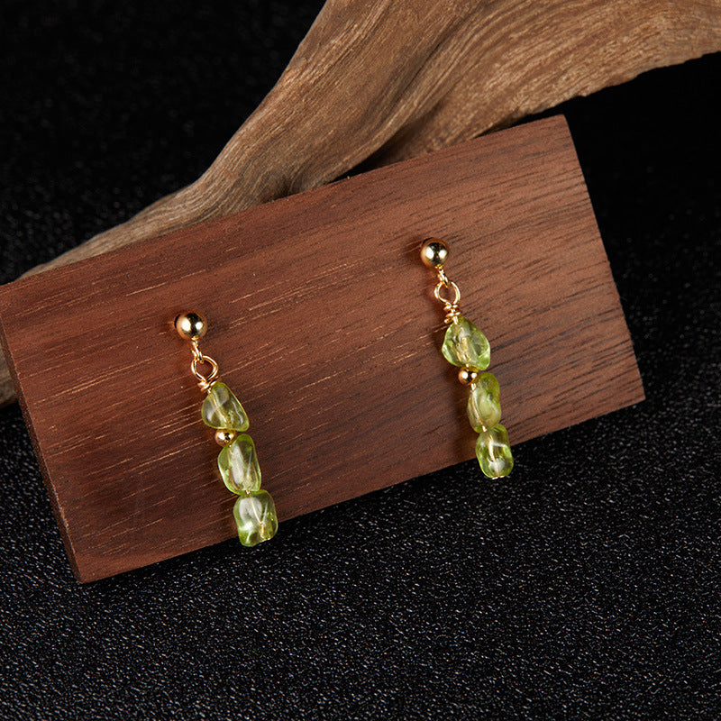 Boucles d'oreilles pendantes en argent plaqué or ornées de pierres de péridot naturelles taillées en forme de gouttes, montées sur une tige dorée.