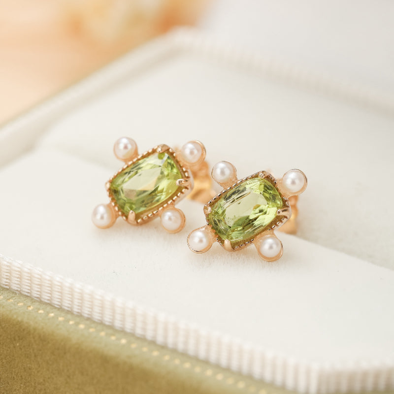 Boucles d'oreilles carrées en argent plaqué or serties d'une pierre centrale péridot verte et de petites perles blanches nacrées sur les côtés.