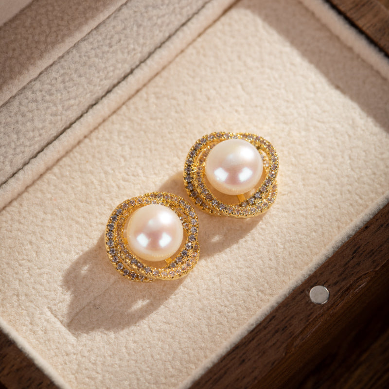 Paire de boucles d'oreilles en argent plaqué or ornées de perles roses et de zircons cubiques scintillants, présentées dans un écrin.