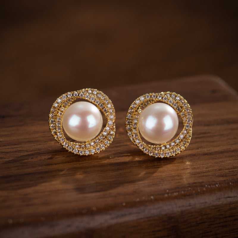 Paire de boucles d'oreilles en argent plaqué or, ornées d'une perle centrale et d'une bordure scintillante de zircons cubiques.