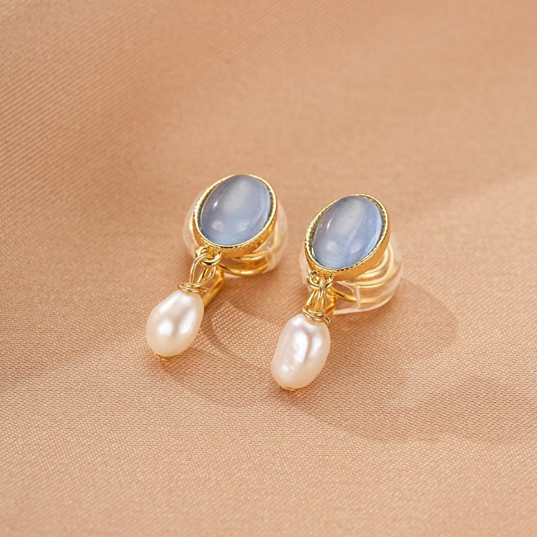 Boucles d’oreilles pendantes dorées avec une pierre bleue ovale et une perle d'eau douce blanche