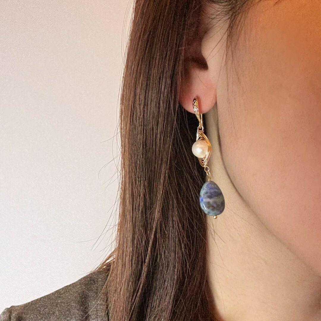 Boucles d'oreilles pendantes élégantes avec perles blanches nacrées et pierres de Lapis Lazuli bleues profondes, montées sur crochets en acier inoxydable doré, idéales pour un look bohème chic ou de cérémonie.