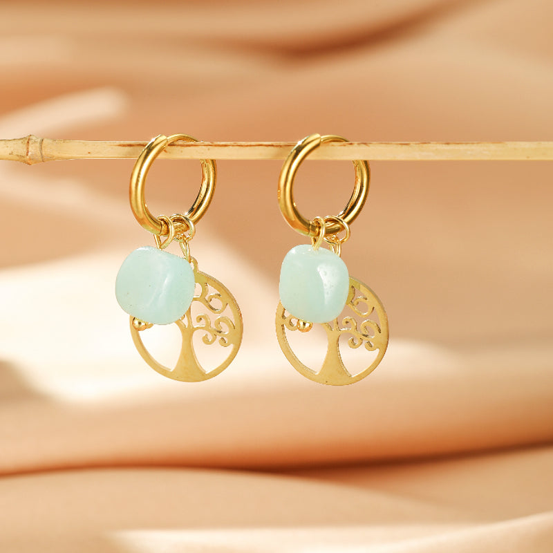 Boucles d'oreilles dorées avec une pierre naturelle bleu pâle et un pendentif Arbre de Vie ajouré.