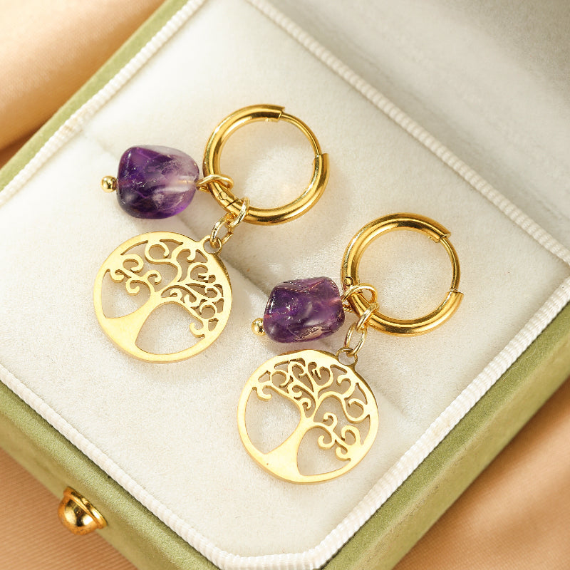 Boucles d'oreilles plaquées or avec pendentifs Arbre de Vie et pierres d'améthyste brutes, présentées dans un écrin vert.