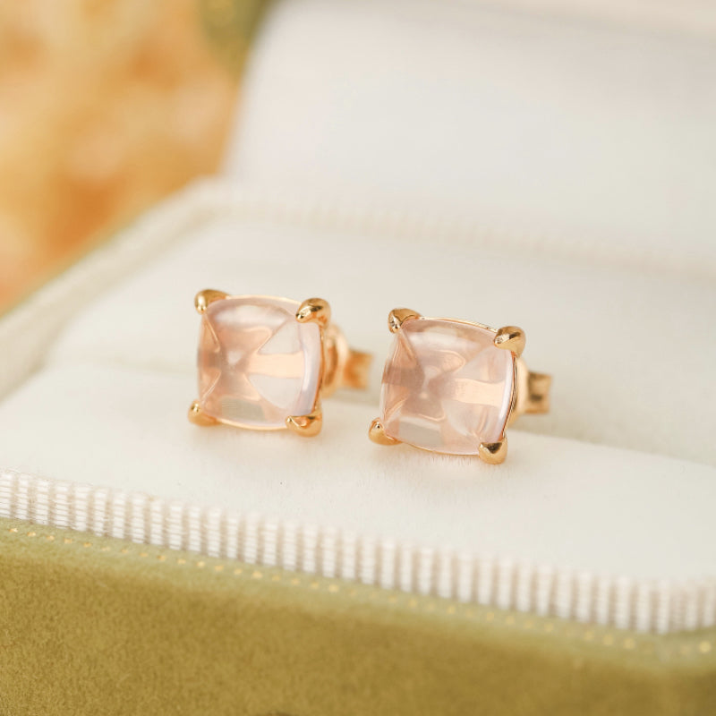 Paire de boucles d'oreilles en quartz rose taillé en coussin, serties sur de l'argent plaqué or rose, présentées dans une boîte à bijoux verte.