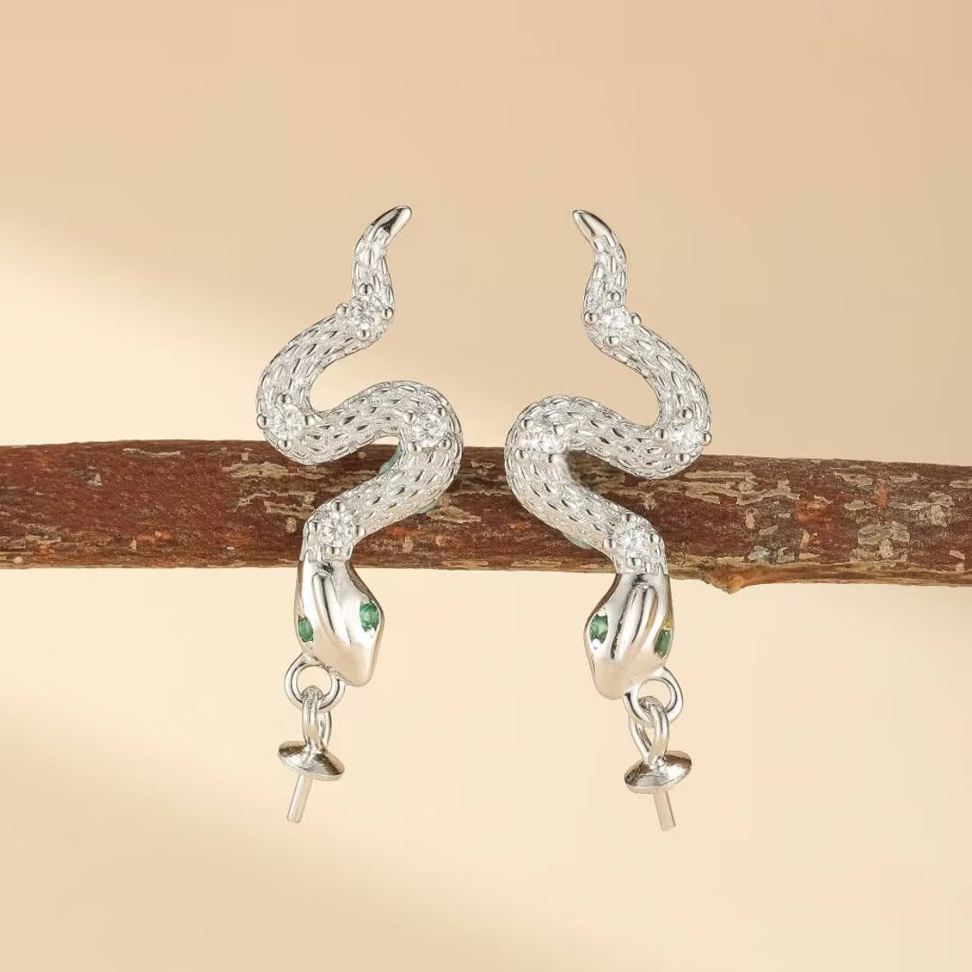 Paires de boucles d'oreilles serpent détaillées en argent 925, ornées de petites pierres vertes pour les yeux.
