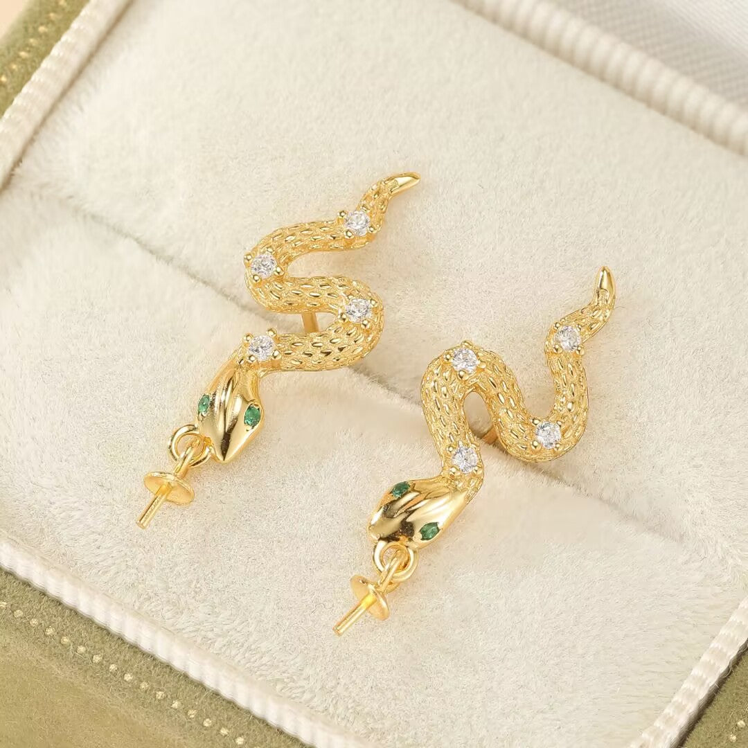 Paire de boucles d'oreilles serpent en argent 925 plaqué or, ornées de zircons et d'émeraudes, présentées dans un écrin.