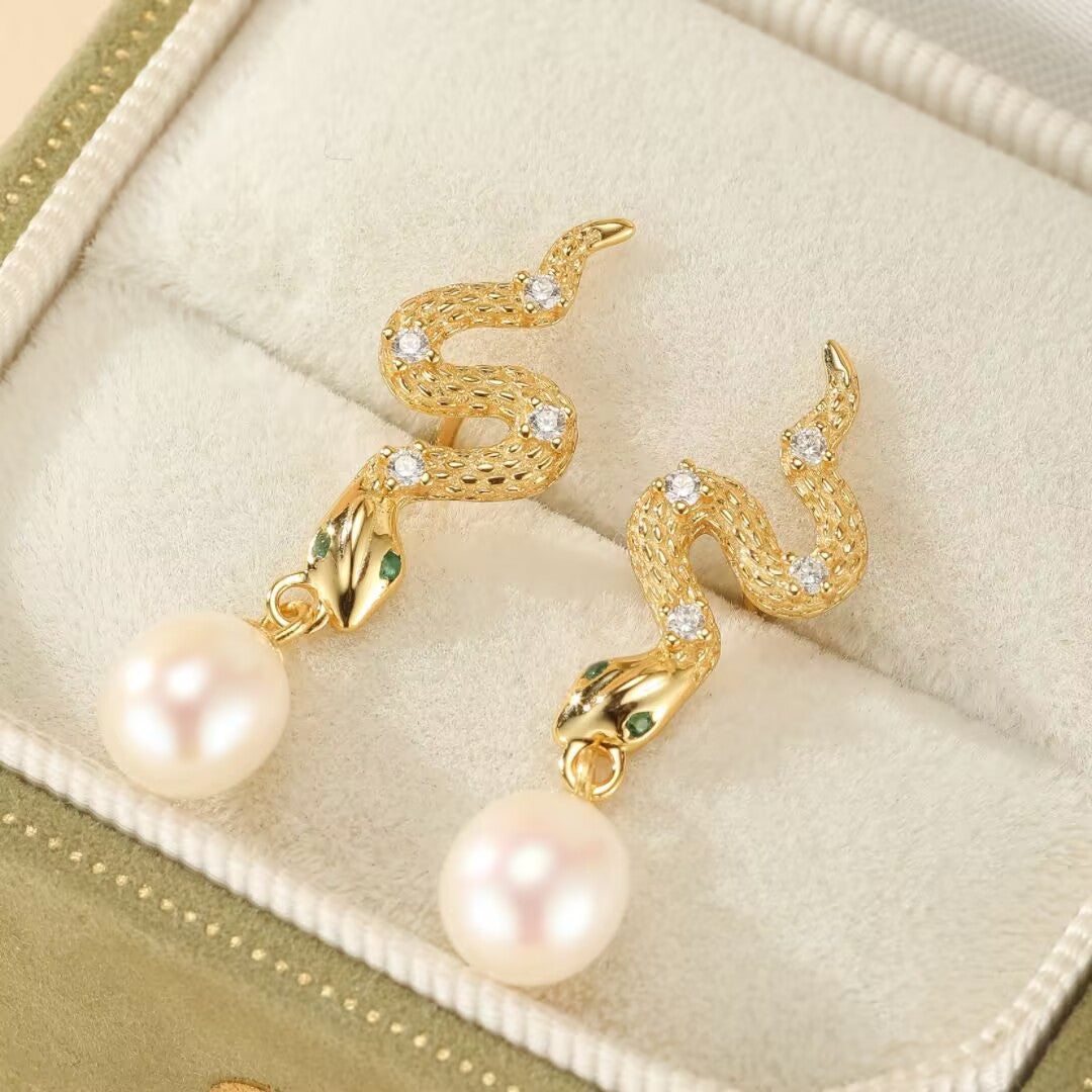 Boucles d'oreilles serpent en argent 925 doré, ornées de perles blanches et de petites pierres vertes pour les yeux.