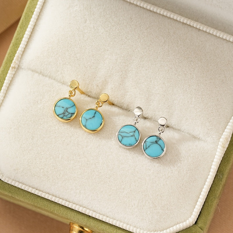 Paire de boucles d'oreilles pendantes rondes en turquoise, montées sur de l'argent et plaqué or, présentées dans un écrin.