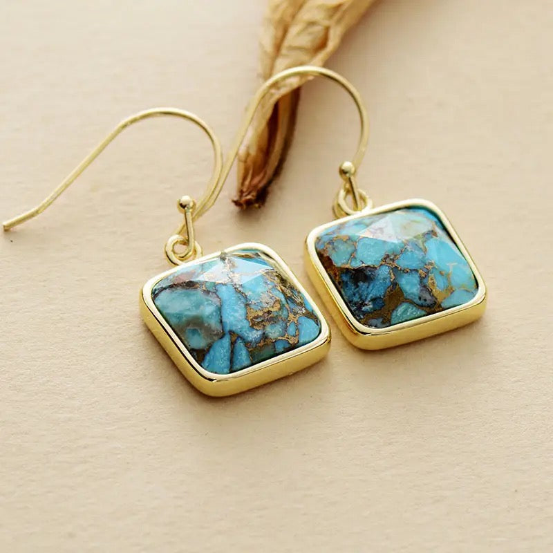 Paire de boucles d'oreilles pendantes en argent plaqué or ornées de pierres carrées bleues turquoise veinées d'or.