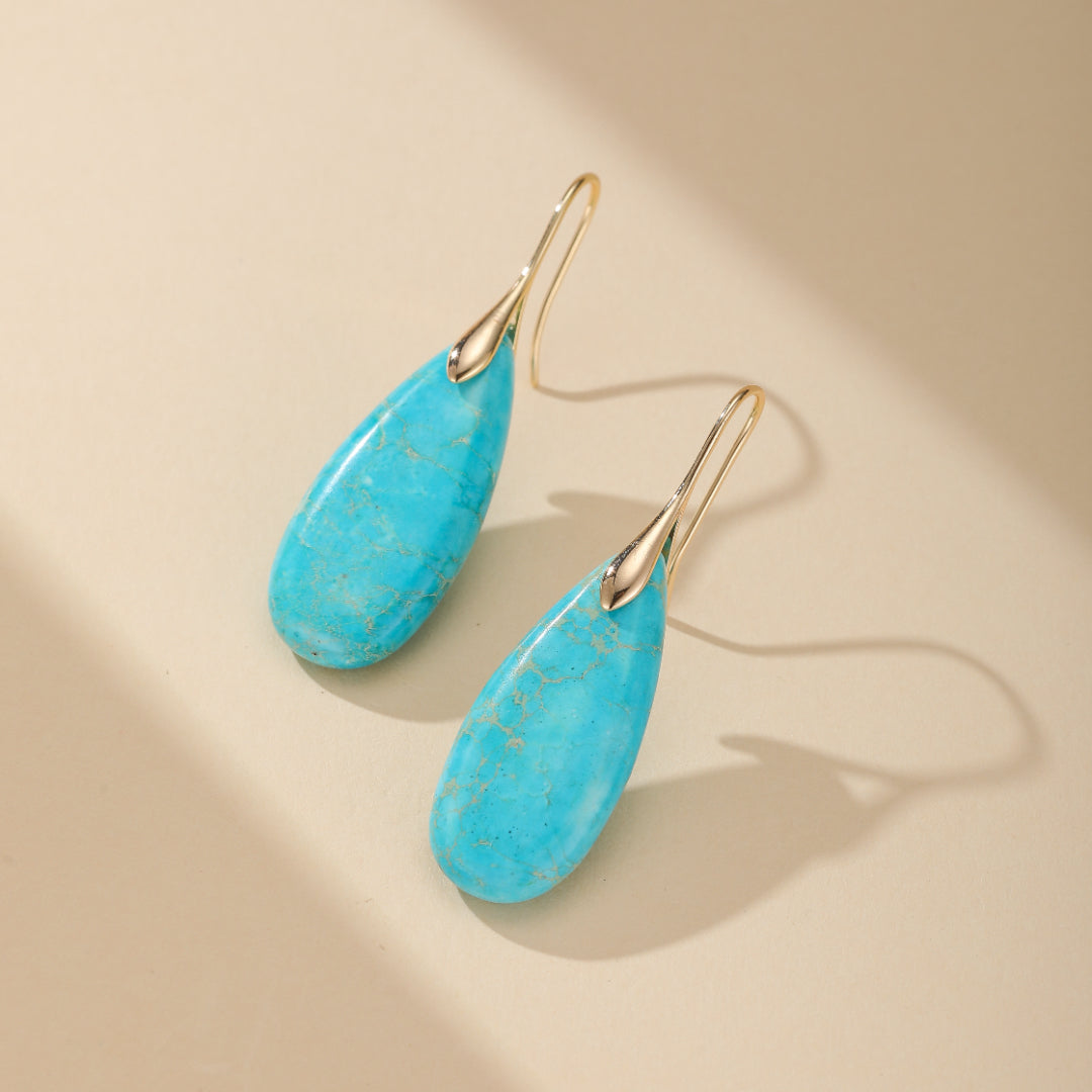 Paire de boucles d'oreilles Majestueuses en turquoise et platine, bijoux spirituels intemporels apportant gentillesse et générosité, symbole de votre voyage intérieur.