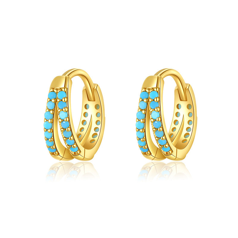 Boucles d'oreilles créoles en argent plaqué or ornées de doubles rangées de petites pierres turquoise bleues, sur fond blanc.