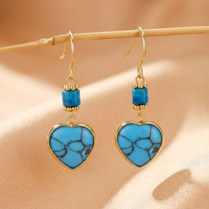 Boucles d'oreilles cœur en turquoise bleue avec des détails dorés et des perles bleues cubiques.