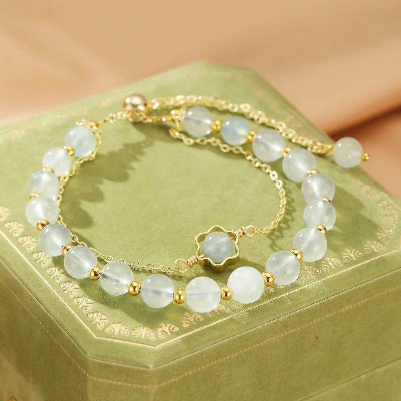 Bracelet "Brillance Océane" en aigue-marine et or, avec une petite fleur en pierre au centre.