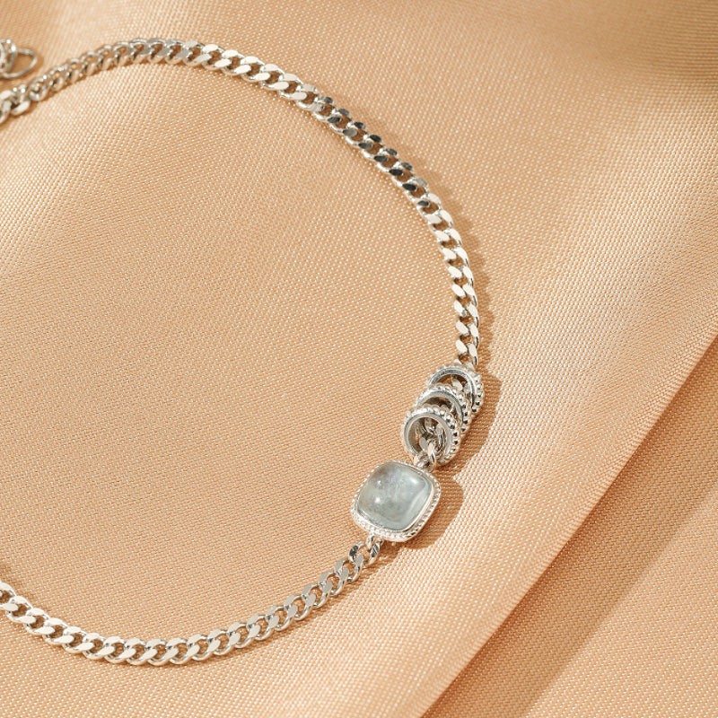 Bracelet "Douceur de Vague" en argent avec une pierre carrée d'aigue-marine centrale et des anneaux décoratifs.
