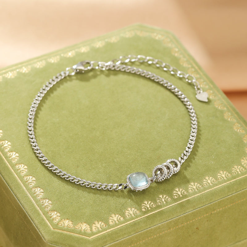 Bracelet "Douceur de Vague" en argent avec une pierre d'aigue-marine carrée et des détails de maillons et d'anneaux.