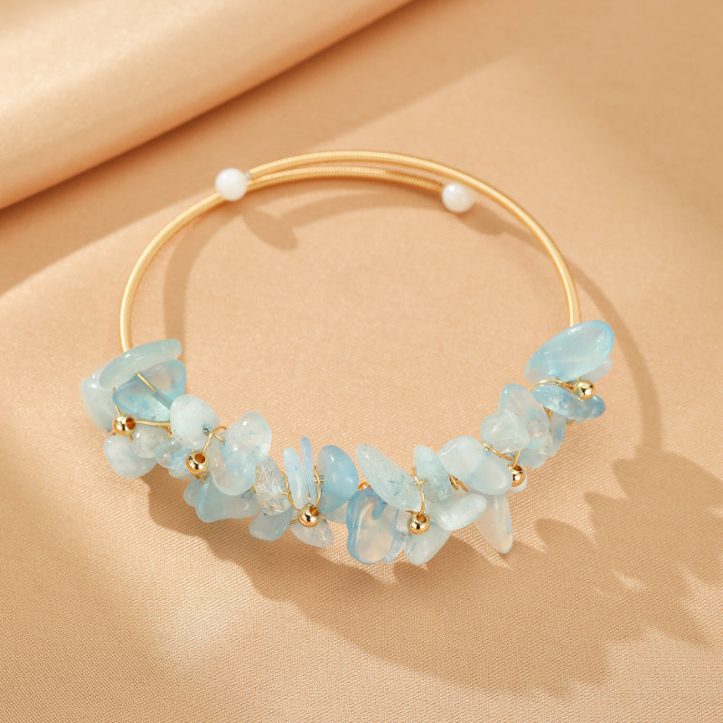 Bracelet jonc rigide doré orné d'aigue-marine brute et de petites perles blanches, style bohème chic.