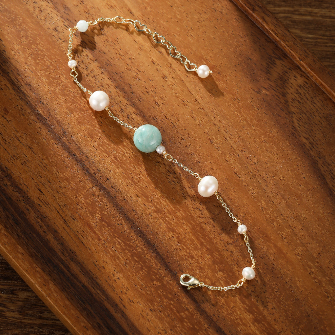 Bracelet en or fin orné d'une perle d'amazonite bleu-vert et de perles de culture nacrées, avec une chaîne délicate à maillons fins et un fermoir mousqueton.