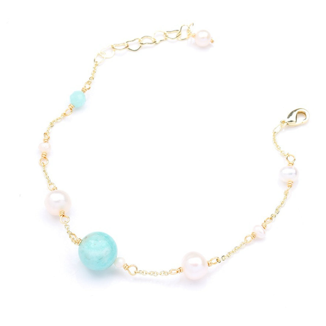Bracelet fin en or jaune orné d'une grande perle d'amazonite turquoise et de perles nacrées roses et blanches sur fond blanc.