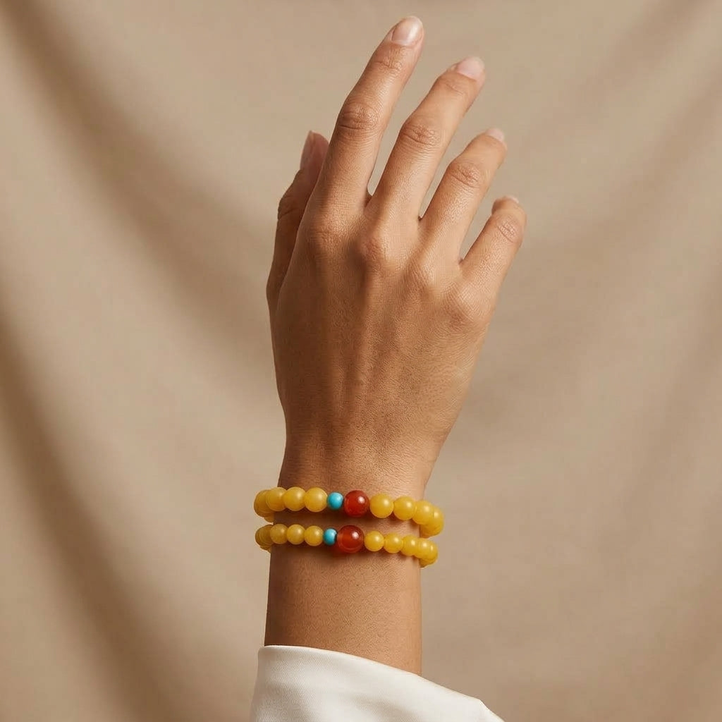 Bracelet Mémoire de la Terre composé de perles d'ambre jaune avec des accents en agate rouge et turquoise porté au poignet