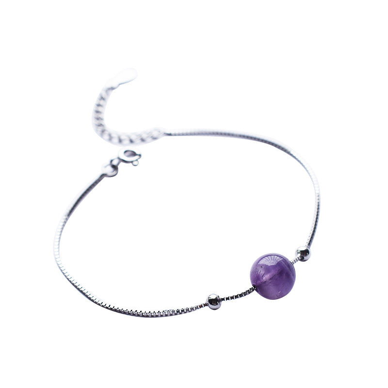 Bracelet fin en argent avec une perle d'améthyste ronde et deux petites perles argentées sur fond blanc.