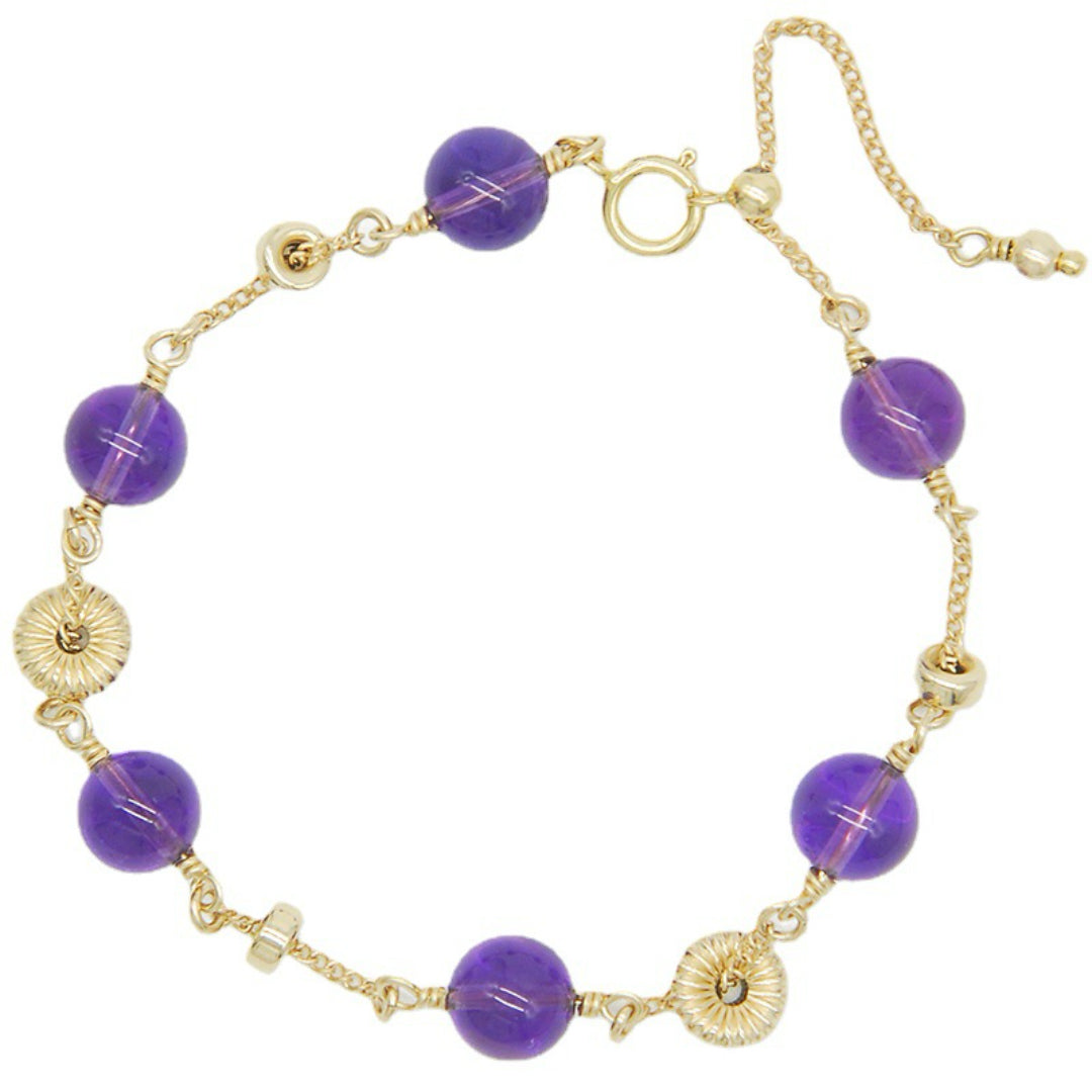 Bracelet en argent doré avec des perles d'améthyste violettes rondes et des disques texturés dorés, fermé par un fermoir mousqueton et une chaîne d'extension.
