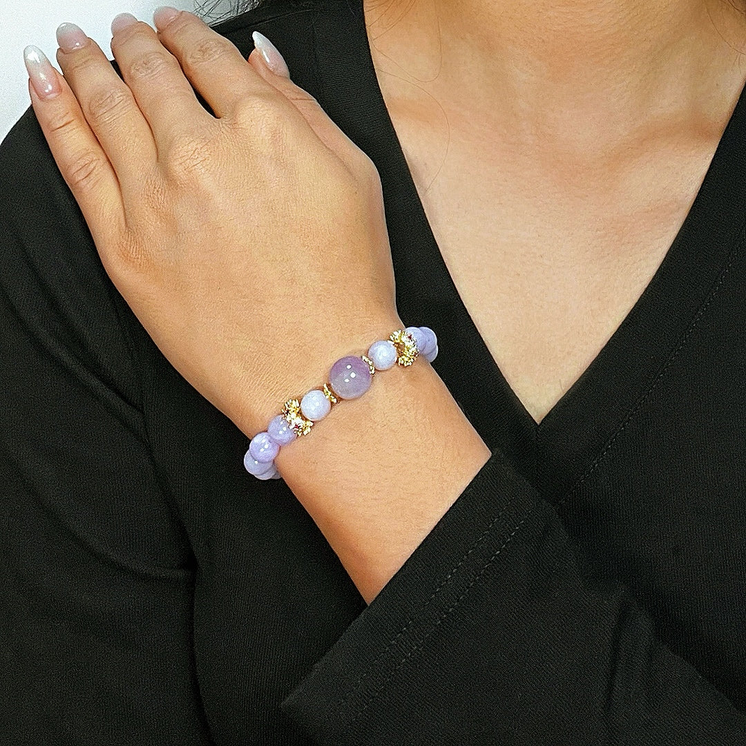 Bracelet en pierres naturelles d'améthyste et de jade avec des détails dorés, porté au poignet d'une femme.