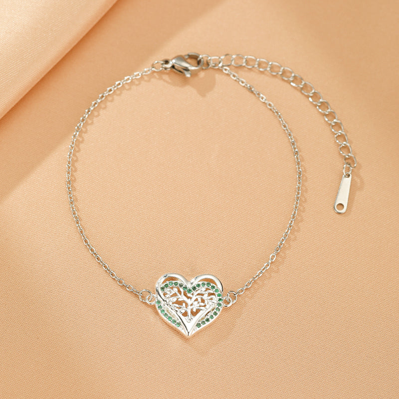 Bracelet Arbre de Vie en argent avec pendentif cœur ajouré serti de petites pierres vertes.