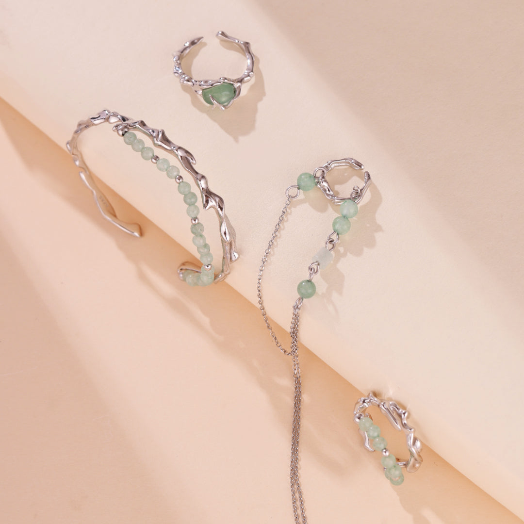 Ensemble de bijoux en argent et aventurine, composé d'un bracelet jonc orné de perles vertes, d'une bague cœur en pierre verte et d'une bague ouverte avec des motifs végétaux.