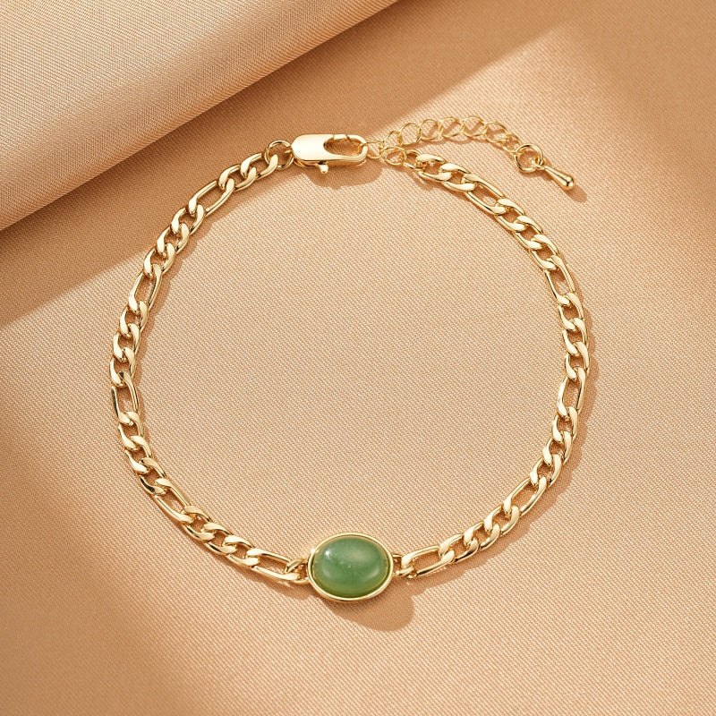 Bracelet en plaqué or avec une pierre d'aventurine verte ovale au centre, chaîne à maillons figaro, fermoir mousqueton réglable.
