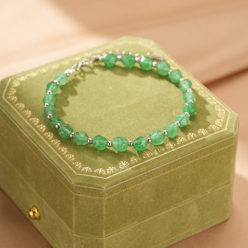 Bracelet en aventurine verte facetée et petites perles rondes en argent, posé sur une boîte à bijoux verte.