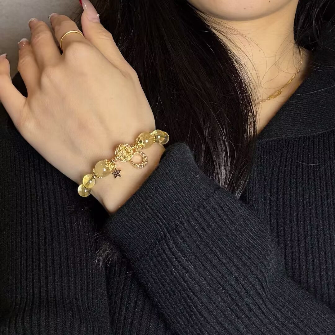Bracelet en citrine avec des breloques lune et étoile dorées, porté au poignet d'une femme