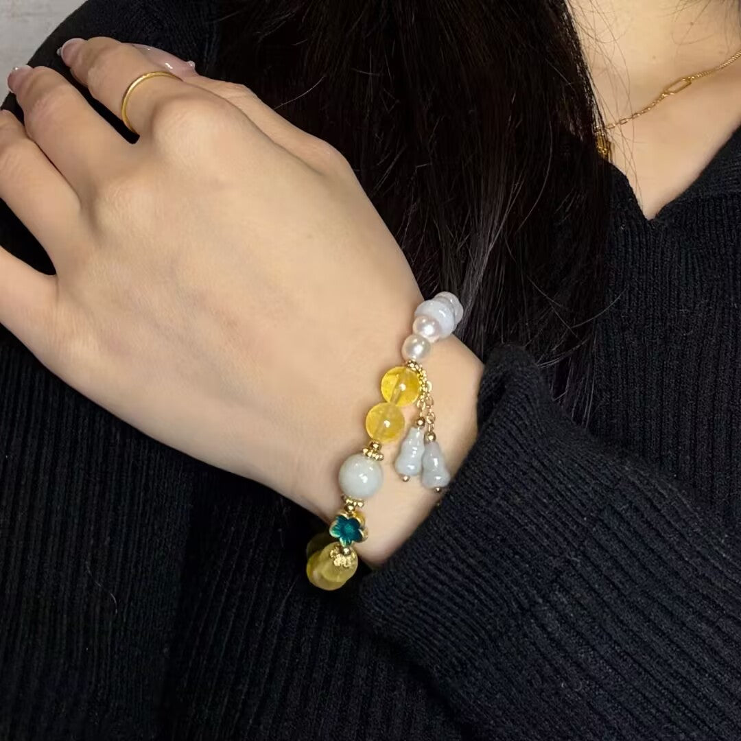 Bracelet fantaisie en perles de citrine, jade et perles blanches, agrémenté de breloques gourdes et d'un pendentif trèfle vert.
