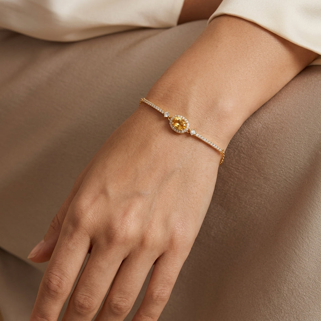 Bracelet Rêve Doré avec pierre centrale citrine ovale entourée de zircons, monté sur une chaîne fine en argent plaqué or portée au poignet.