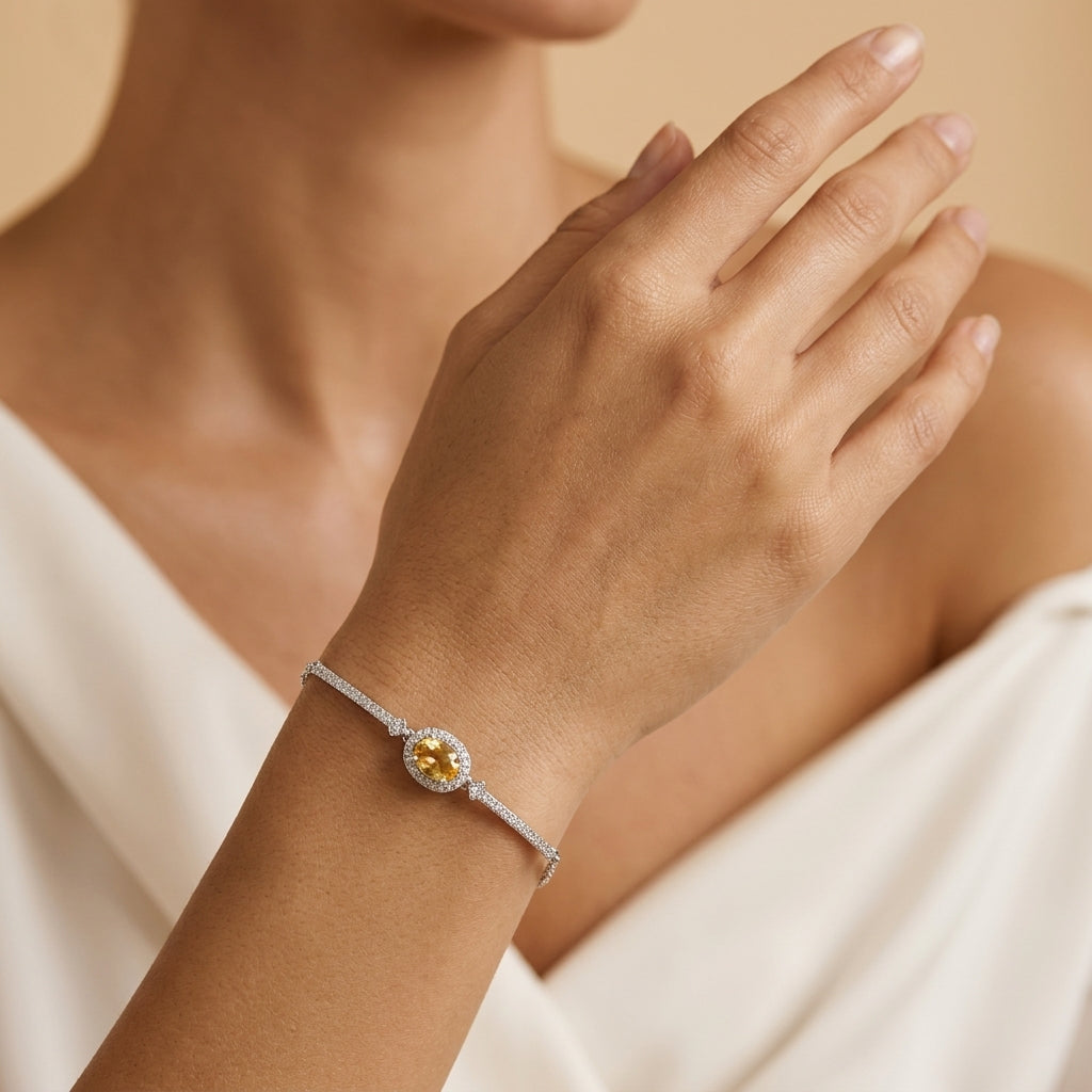Bracelet Rêve Doré en argent plaqué or orné d'une pierre de citrine ovale entourée de zircons, porté au poignet d'une femme.